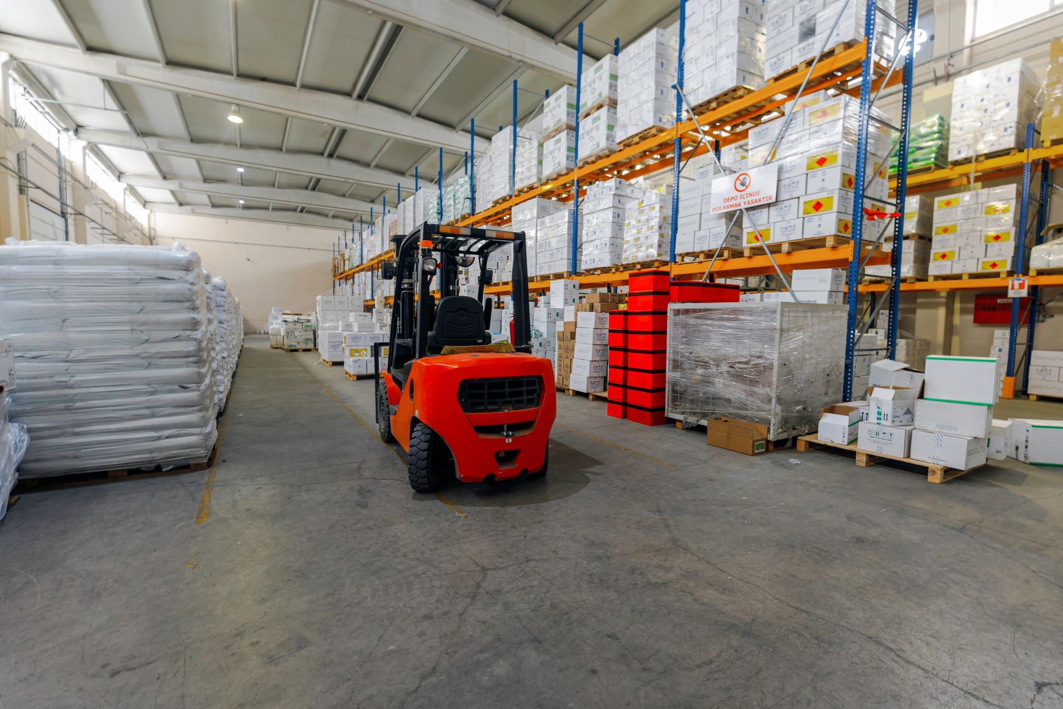 Forklift moving goods in a warehouse aisle